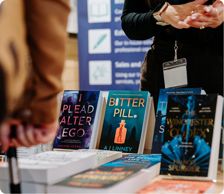Books displayed at a publishing event with author engaging readers