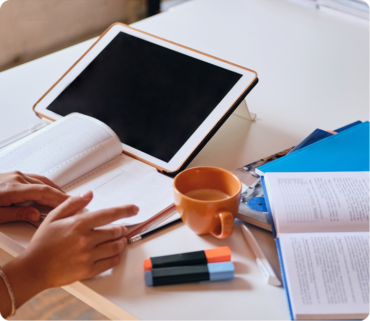 Writer planning an ebook with notebook, tablet and books on a desk
